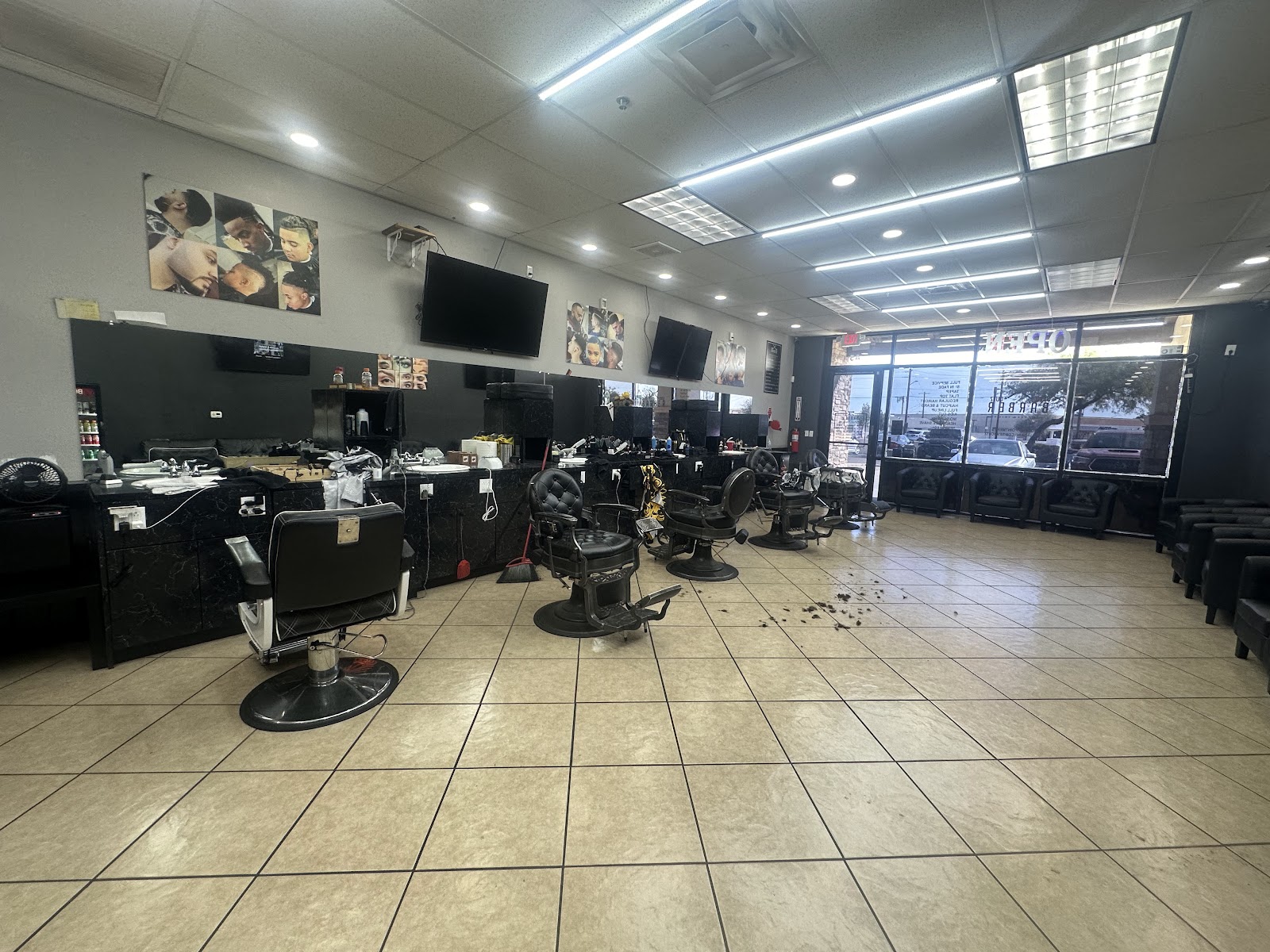 Inside our shop: a row of black barber chairs and marble stations in the daylight from our front windows