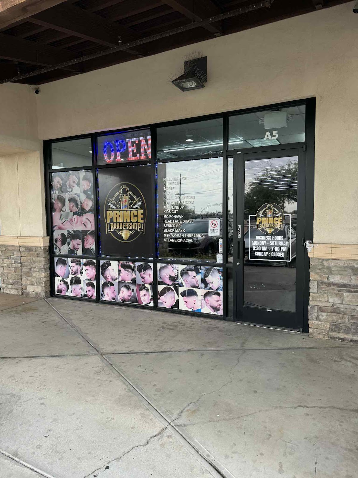 Our storefront at suite A5: the gold Prince crest on black glass above the stacked stone, with our style boards in the windows